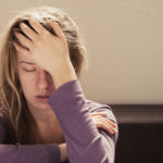 image of overwhelmed girl with her eyes closed and her hand to her forehead